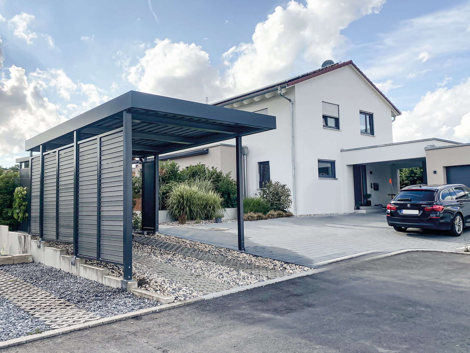 Einzelcarport von Siebau mit seitlichen Sichtschutzelementen. Aufbau auf Winkelstein-Mauer. E-Panel für bauseitige Ladestation