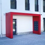 Vordach der Serie S.1 von Siebau in U-Form. Fassadenplatten in rot