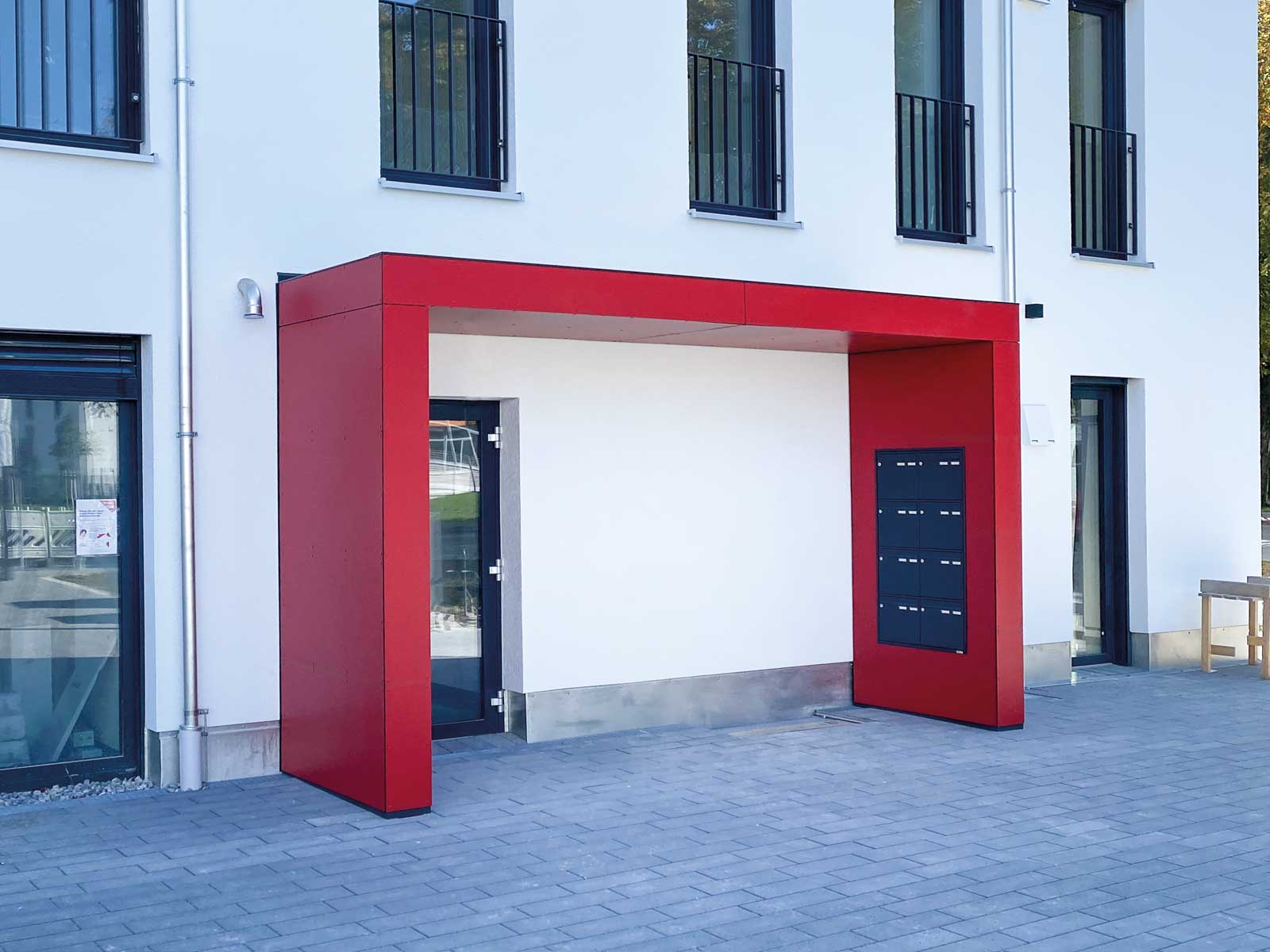 Vordach der Serie S.1 von Siebau in U-Form. Fassadenplatten in rot
