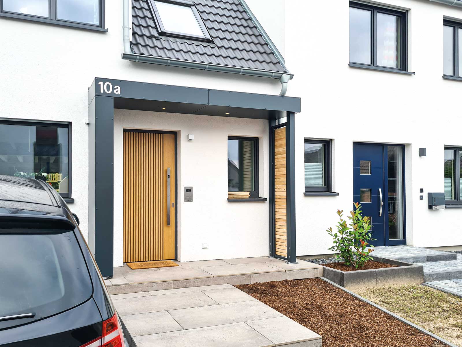 Vordach Serie S1 von Siebau. Zwei Stützen an der offenen Seite mit Sichtschutzelement Holzlattung